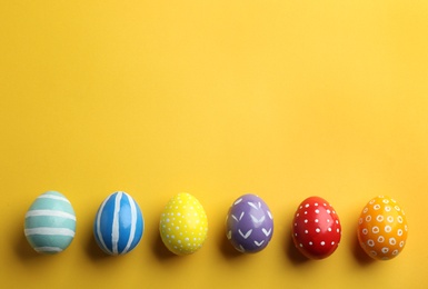 Flat lay composition of painted Easter eggs on color background, space for text