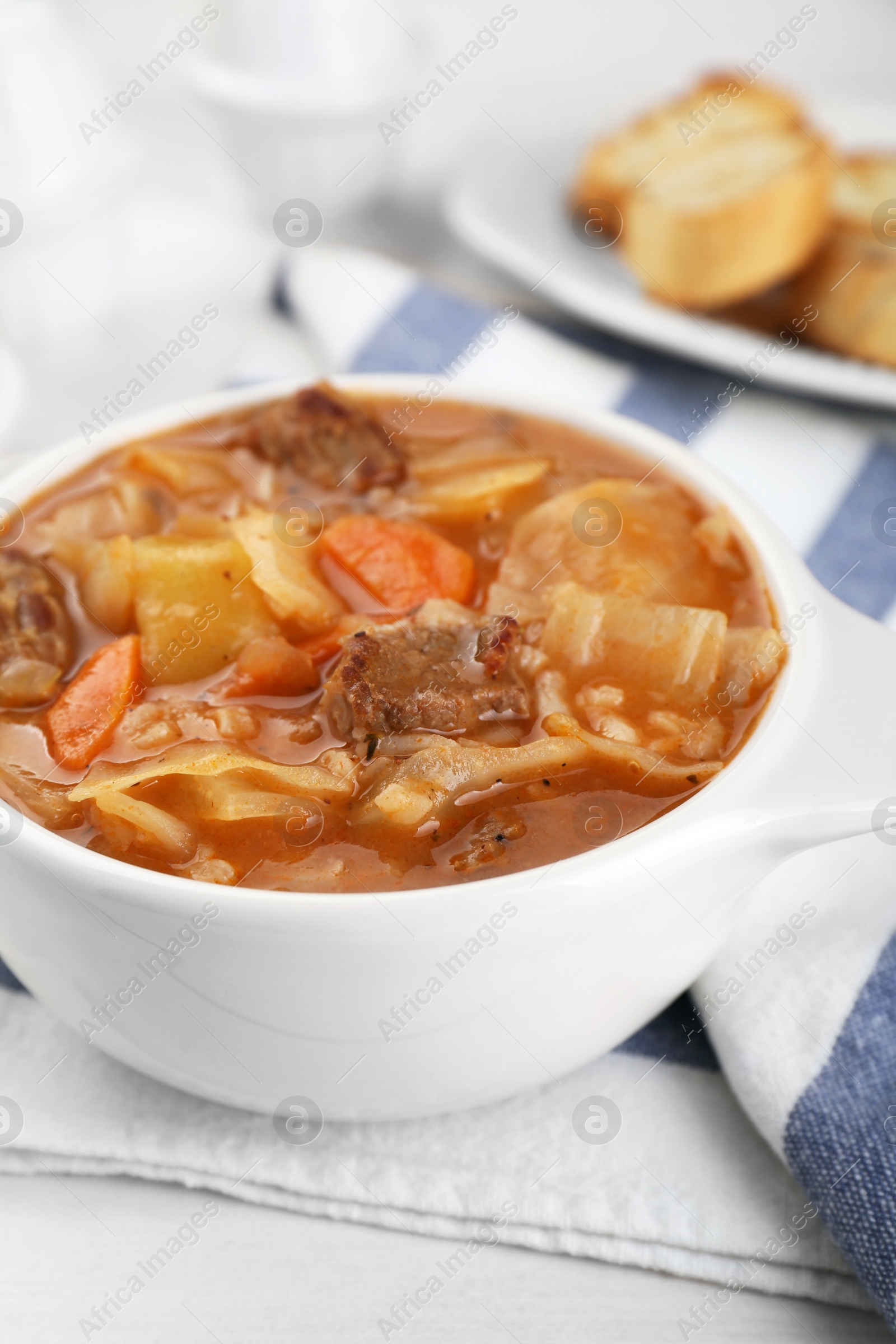 Photo of Tasty cabbage soup with meat and carrot on white wooden table, closeup