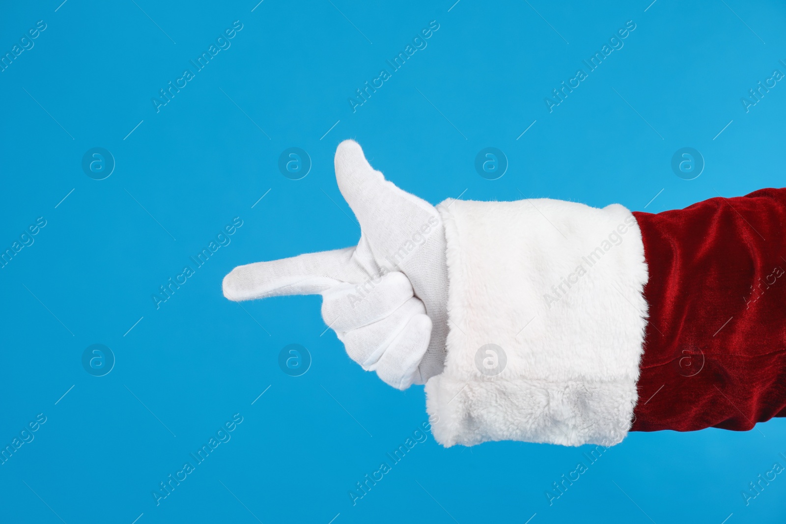 Photo of Santa Claus pointing at something on blue background, closeup of hand