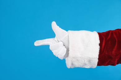 Santa Claus pointing at something on blue background, closeup of hand