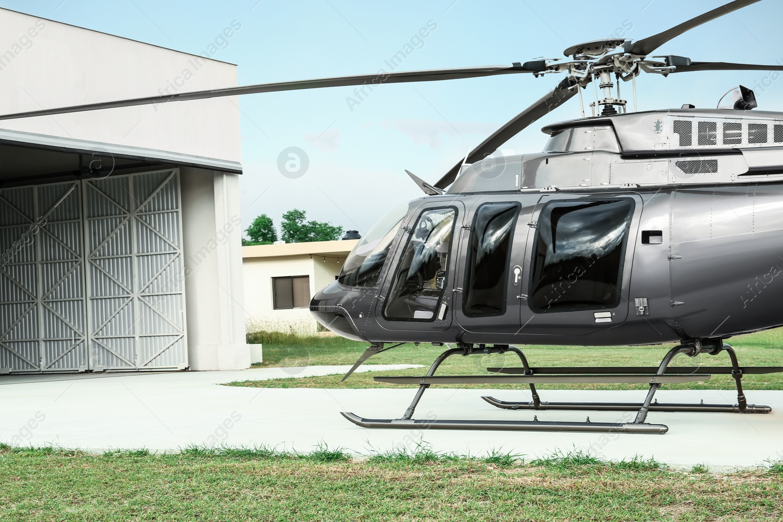 Photo of Beautiful helicopter on helipad in field near hangar