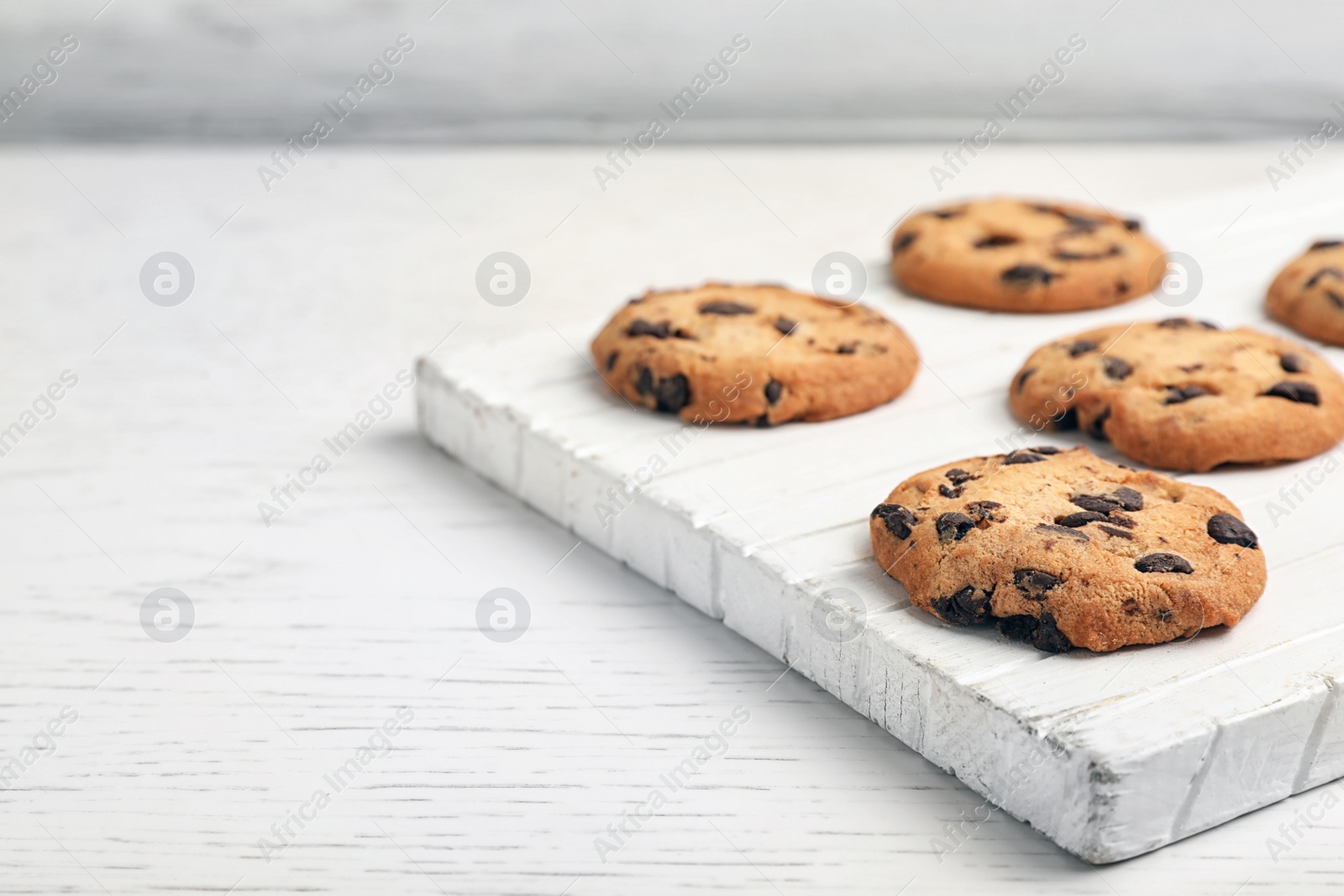 Photo of Wooden board with tasty chocolate cookies on light table