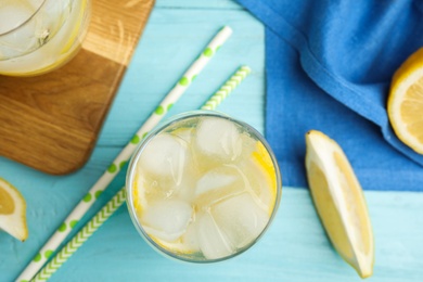 Soda water with lemon slices and ice cubes on light blue wooden table, flat lay