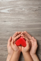 Photo of Woman and child holding heart on wooden background, top view with space for text. Donation concept