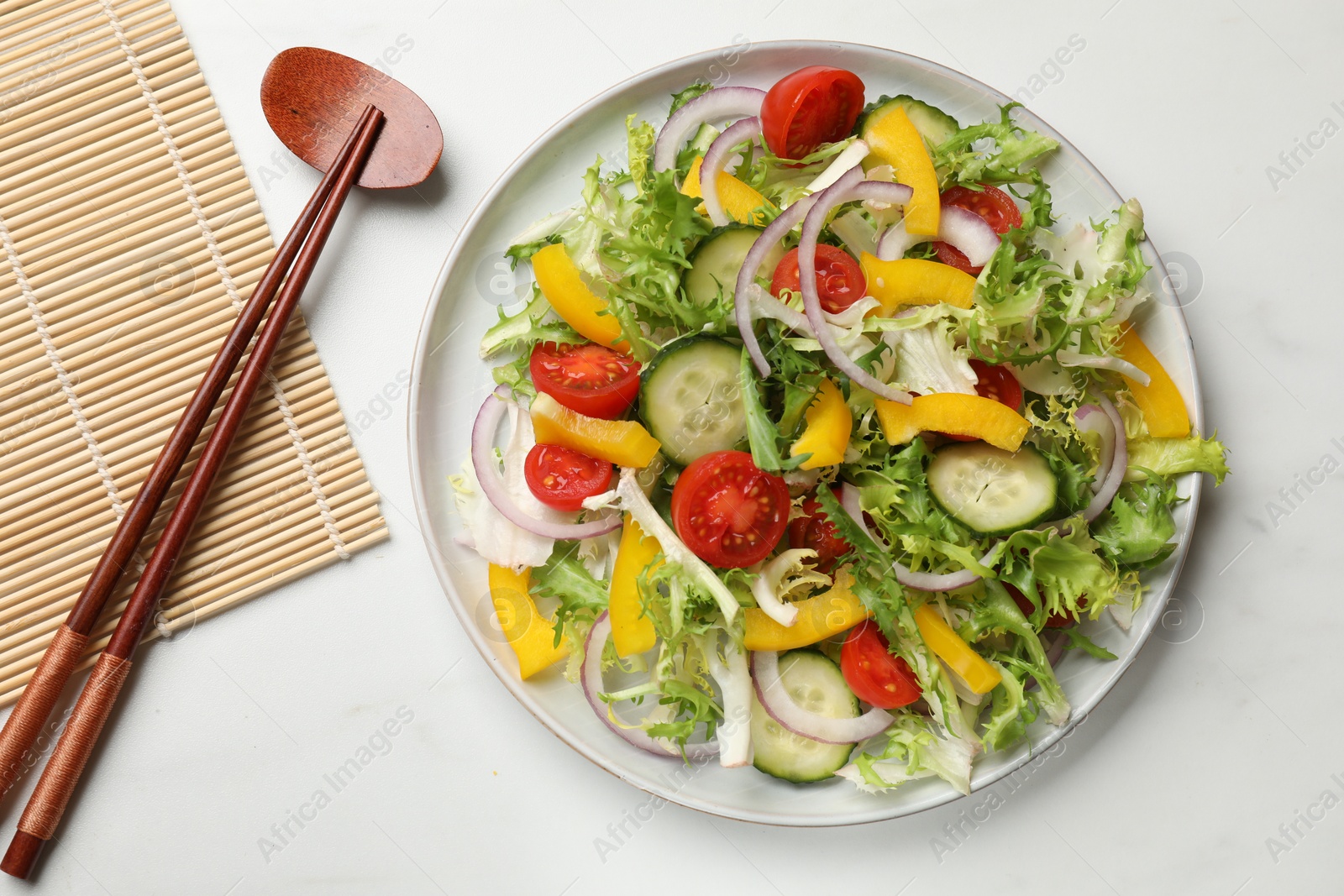 Photo of Tasty fresh vegetarian salad and chopsticks on white marble table, top view