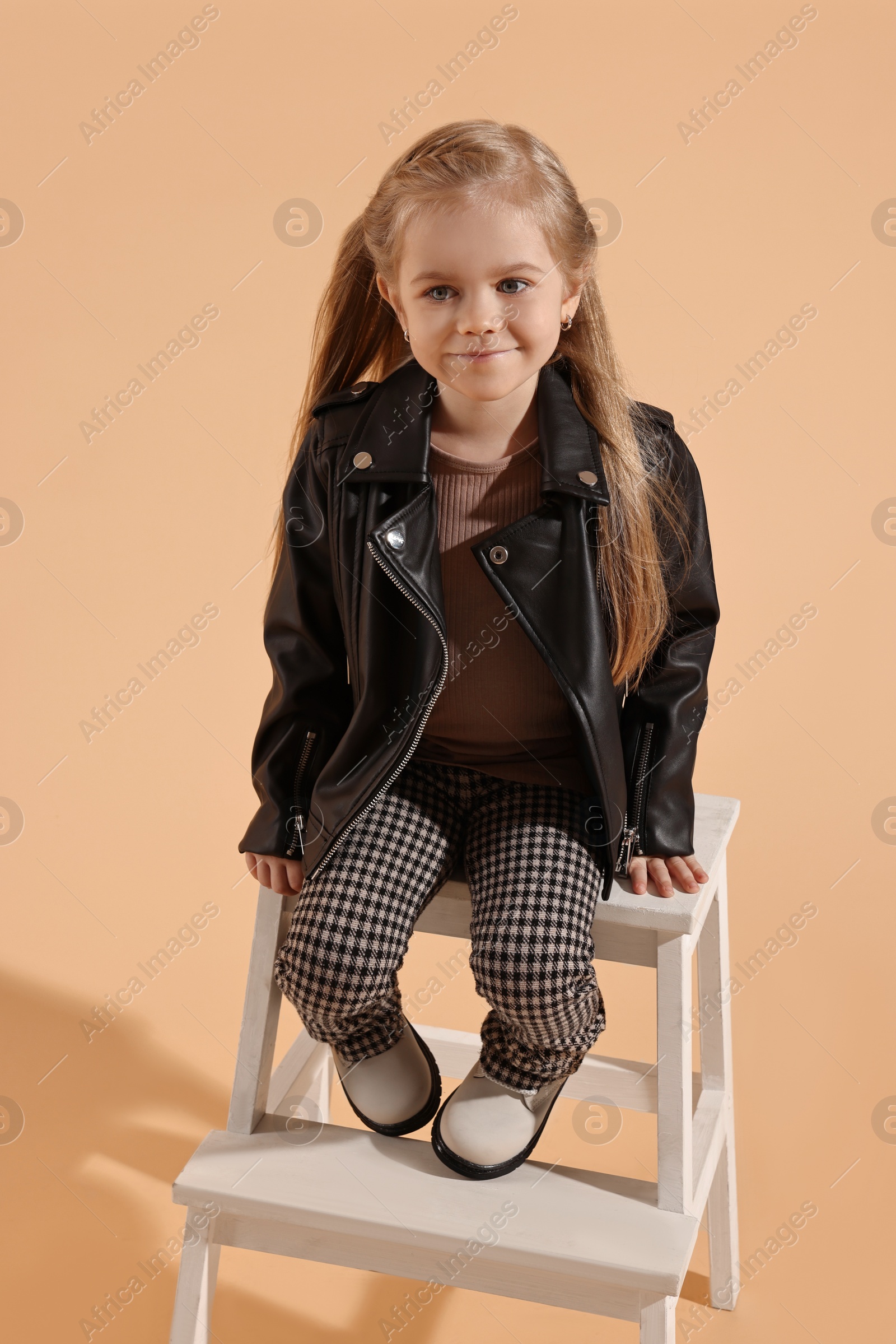 Photo of Fashion concept. Stylish girl posing on pale orange background