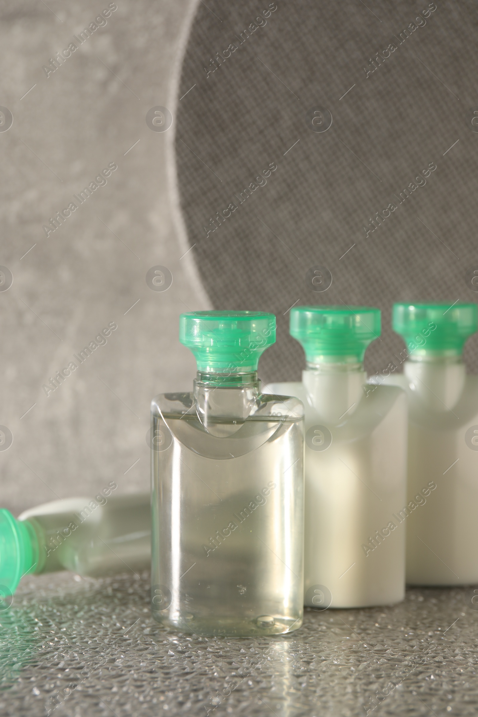 Photo of Mini bottles of cosmetic products on grey textured table