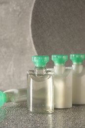 Mini bottles of cosmetic products on grey textured table