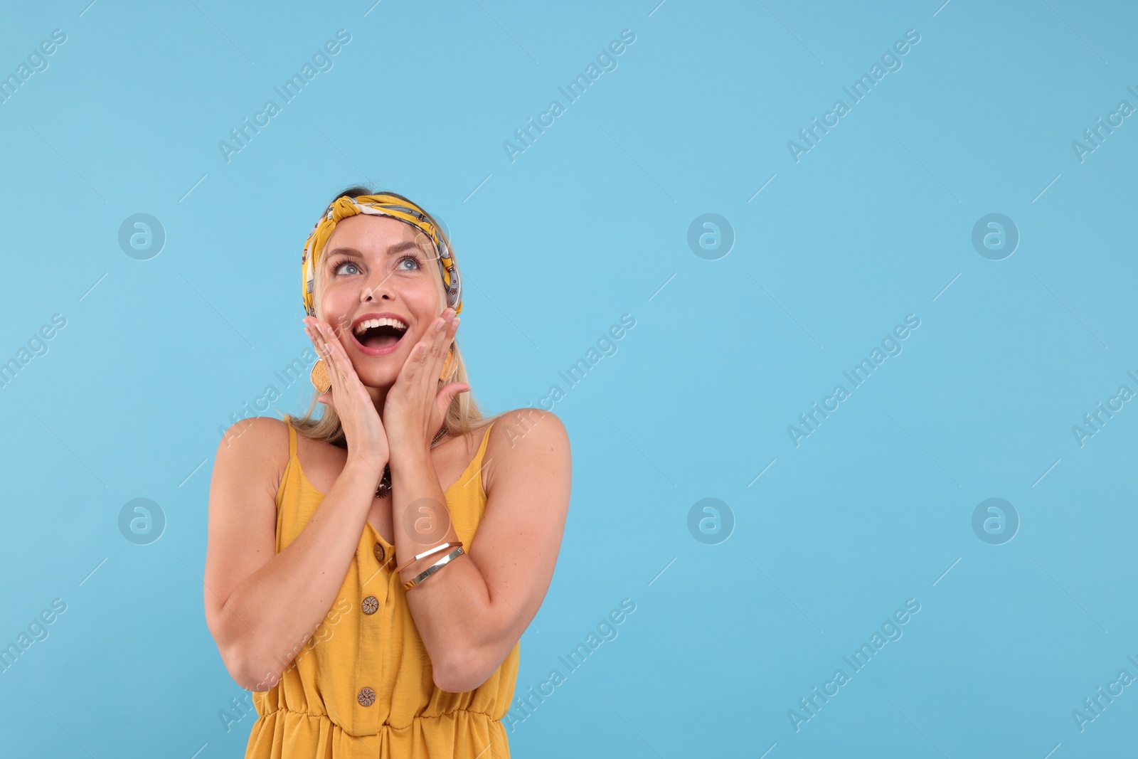 Photo of Portrait of surprised hippie woman on light blue background. Space for text