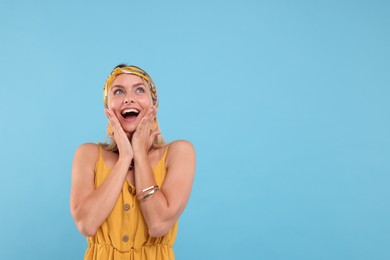 Photo of Portrait of surprised hippie woman on light blue background. Space for text