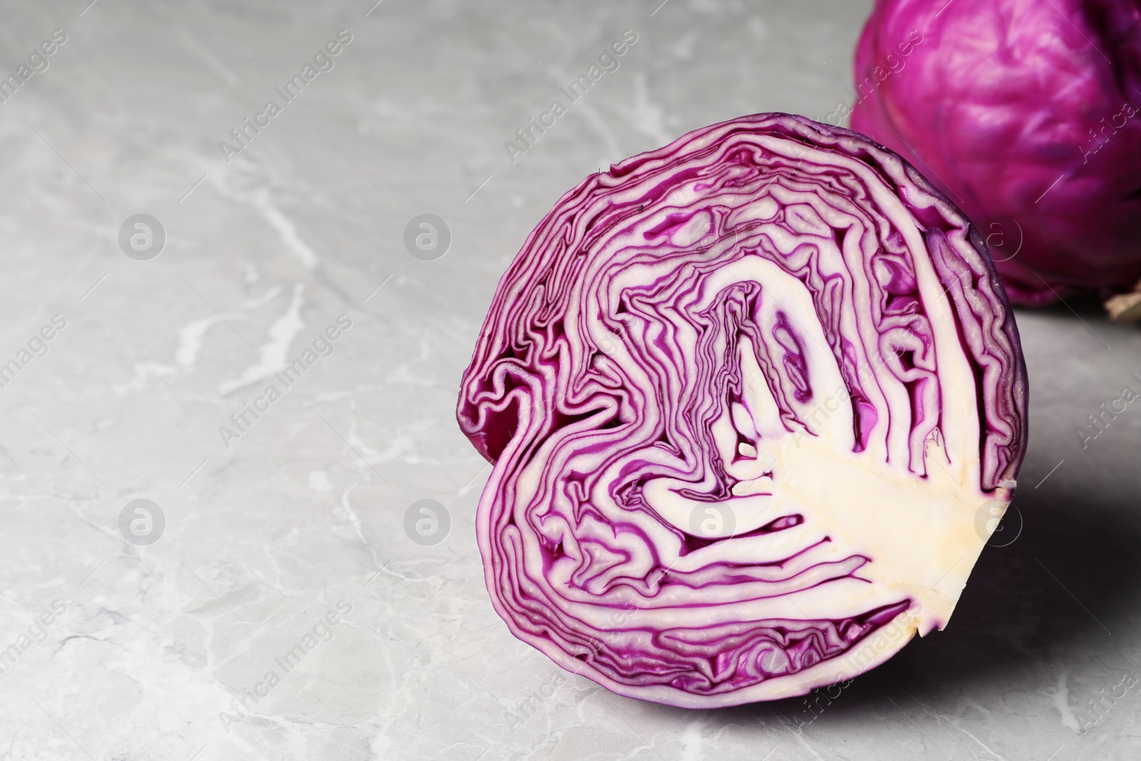 Photo of Half of fresh red cabbage on light grey marble table, space for text