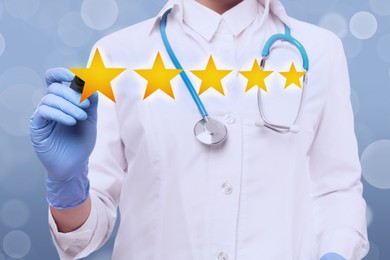 Image of Stars as symbol of quality rating. Doctor using virtual screen on light blue background, closeup