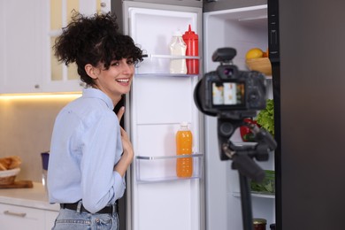 Photo of Smiling food blogger explaining something while recording video in kitchen