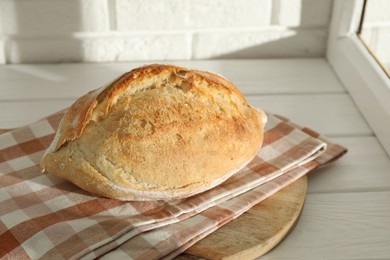 Photo of Freshly baked sourdough bread on white wooden table indoors