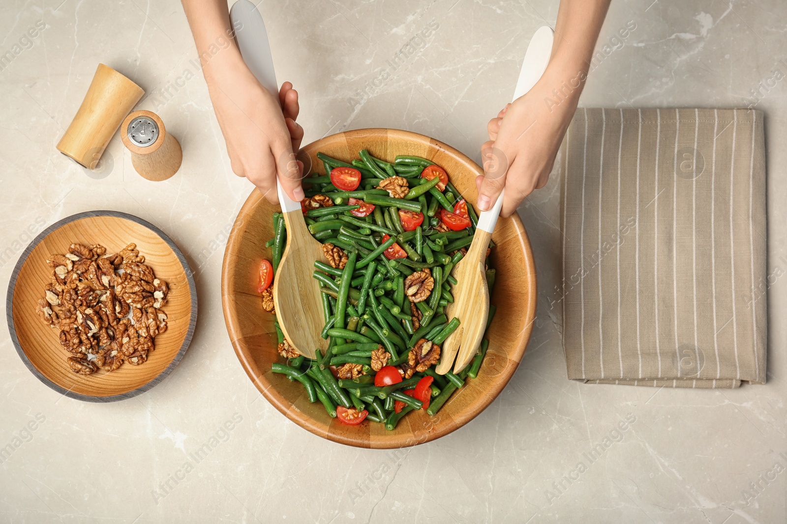 Photo of Woman preparing healthy salad with green beans, cherry tomatoes and walnuts at table