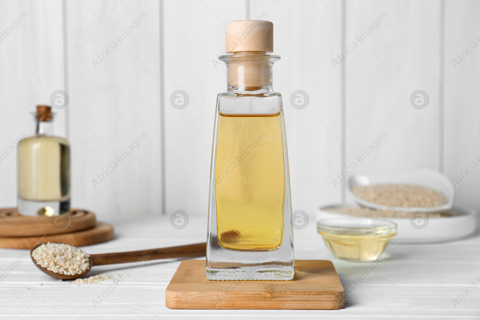 Photo of Sesame oil and seeds on white wooden table