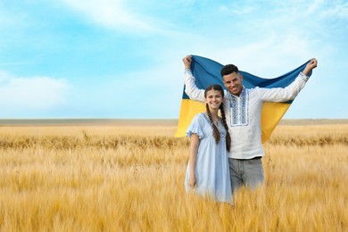 Friends holding national flag of Ukraine in field. Space for text