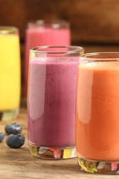 Photo of Glasses with different tasty smoothies on wooden table