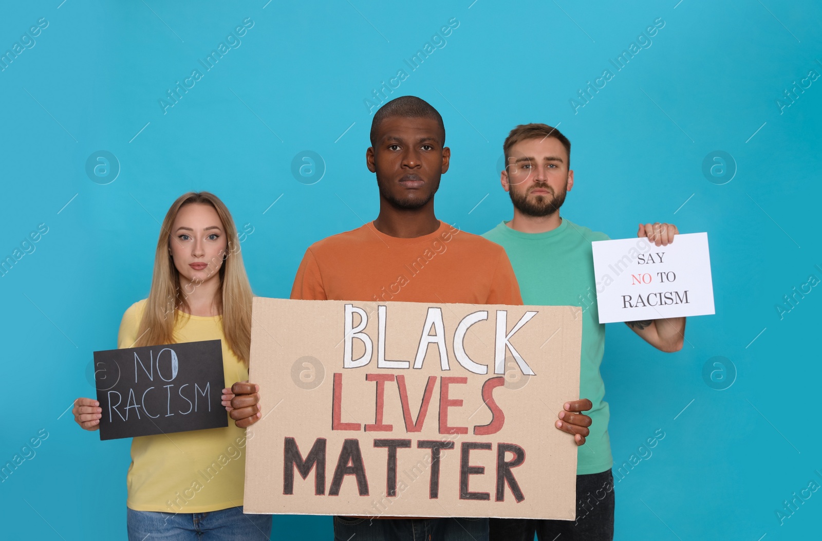 Photo of Group of people holding signs on light blue background. Racism concept