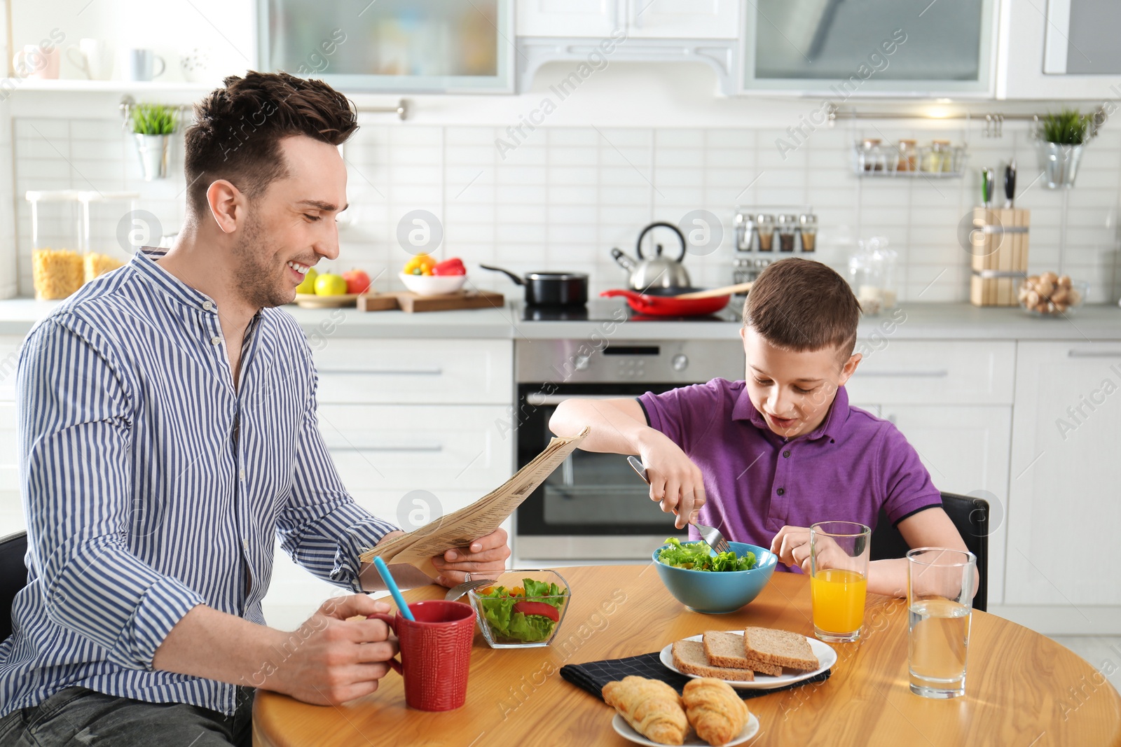 Photo of Dad and son having breakfast together in kitchen