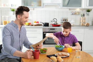 Dad and son having breakfast together in kitchen