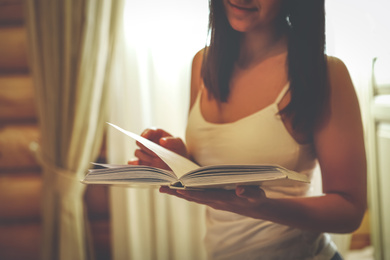 Young woman reading book at home, closeup