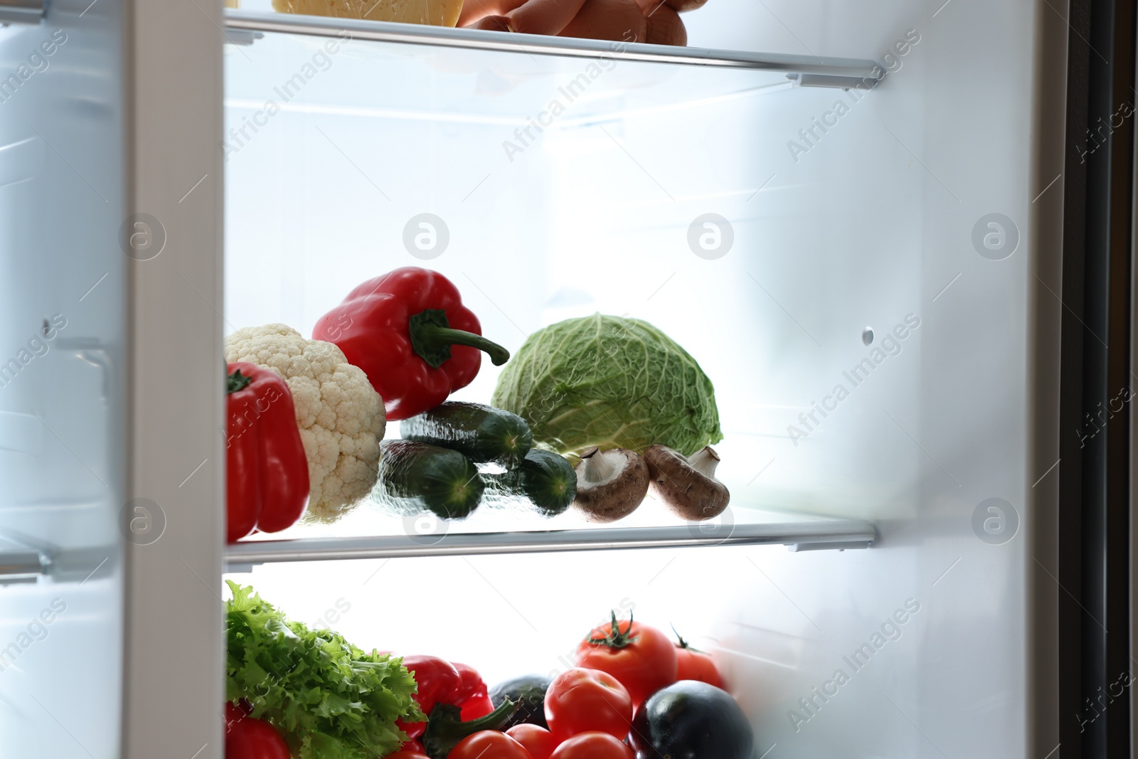 Photo of Open refrigerator full of different products indoors