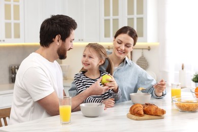 Happy family having breakfast at table in kitchen