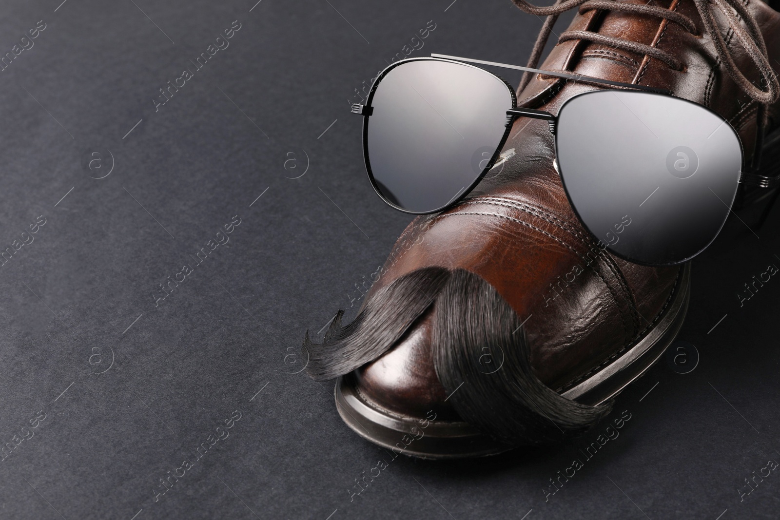 Photo of Artificial moustache, shoe and sunglasses on black background, closeup. Space for text