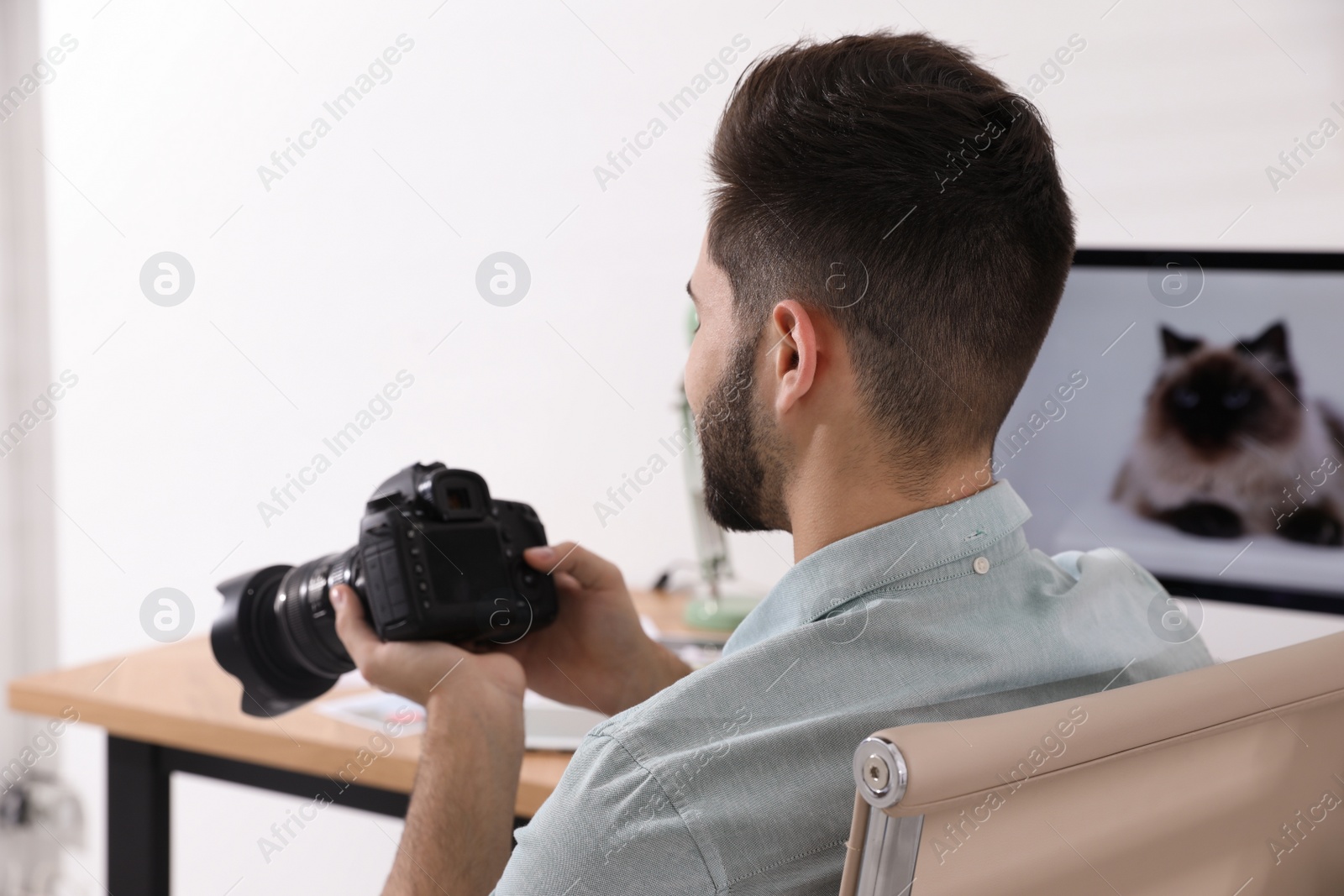Photo of Professional photographer with camera working at table in office