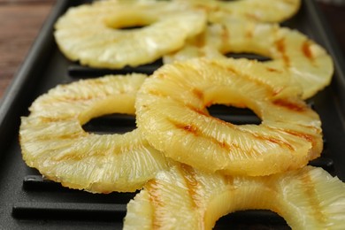 Tasty grilled pineapple slices on grill tray, closeup