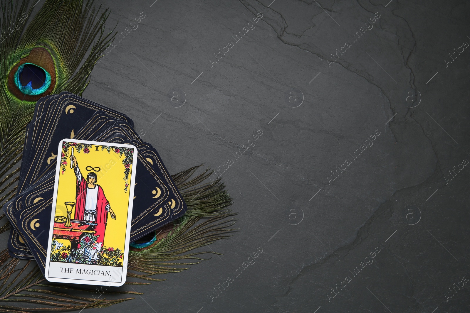 Photo of The Magician and other tarot cards with peacock feathers on black table, flat lay. Space for text