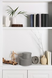 Photo of Shelving unit with clock, books and different decor indoors. Interior design