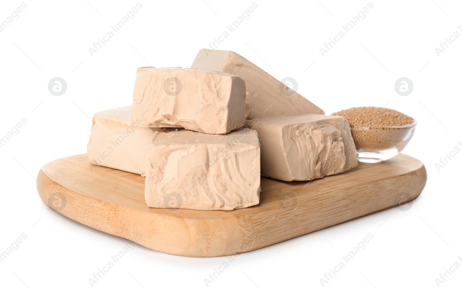 Photo of Wooden board with pieces of compressed yeast on white background