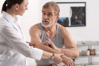 Photo of Orthopedist examining patient with injured arm in clinic