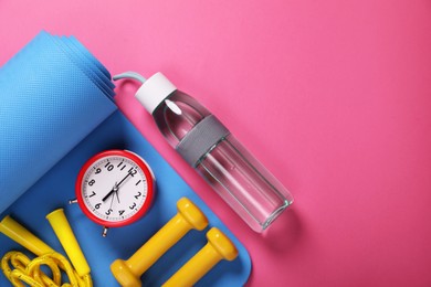 Photo of Alarm clock, bottle of water and sports equipment on pink background, flat lay with space for text. Morning exercise