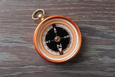 Photo of One compass on wooden table, top view