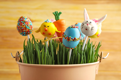 Photo of Delicious sweet cake pops in bucket with grass. Easter holiday