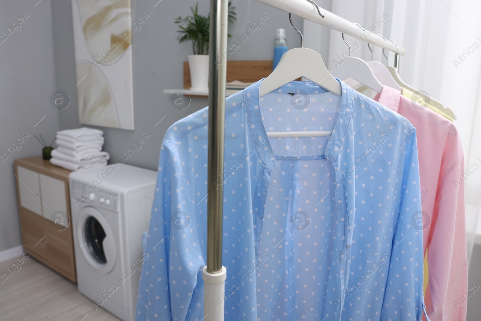 Photo of Rack with different clothes in laundry room