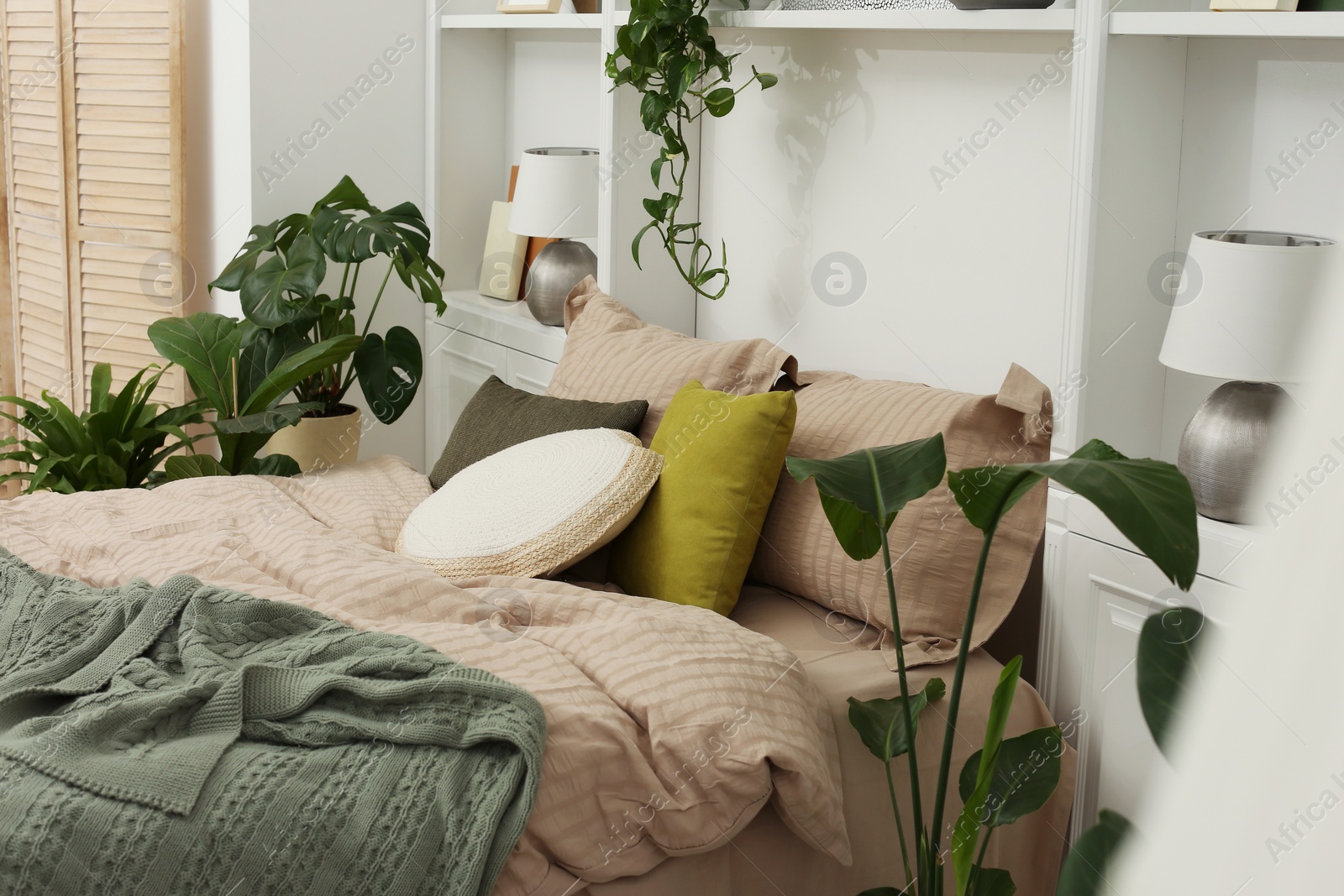 Photo of Comfortable bed and different houseplants in bedroom. Interior design