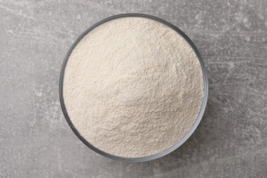 Photo of Glass bowl with quinoa flour on light grey table, top view