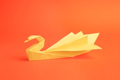 Photo of Origami art. Paper swan on orange background,