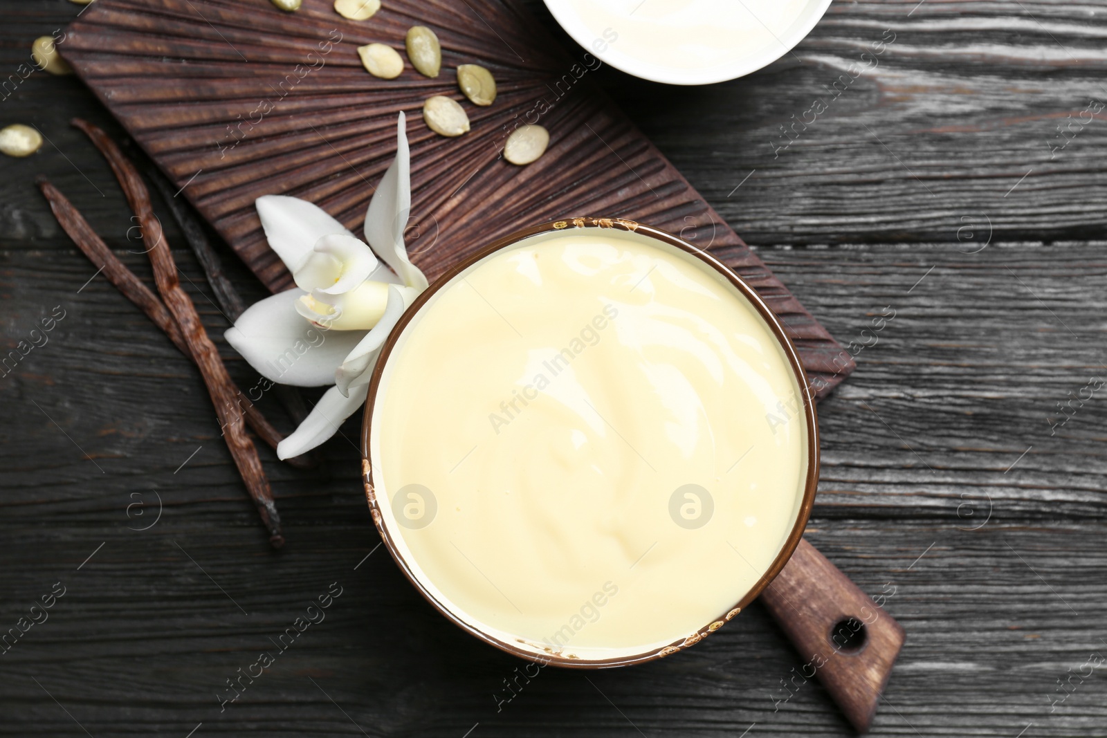 Photo of Vanilla pudding, sticks and flower on wooden background