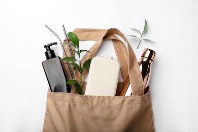 Bag with eco friendly products on white background, top view