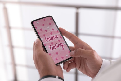 Image of Man visiting dating site via smartphone indoors, closeup