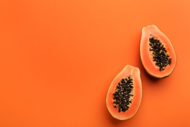Photo of Fresh halved papaya fruit on orange background, flat lay. Space for text