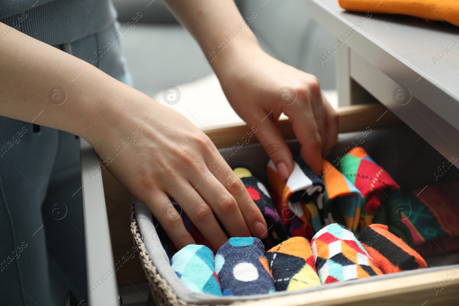 Photo of Woman putting socks into drawer indoors, closeup