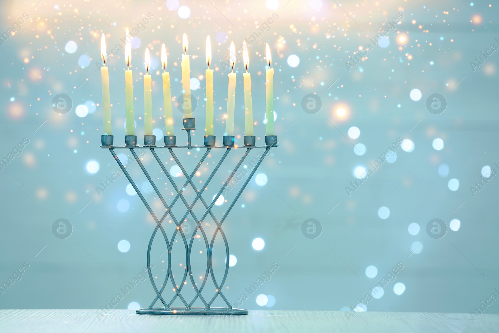 Image of Hanukkah celebration. Menorah with burning candles on table against blurred lights, space for text