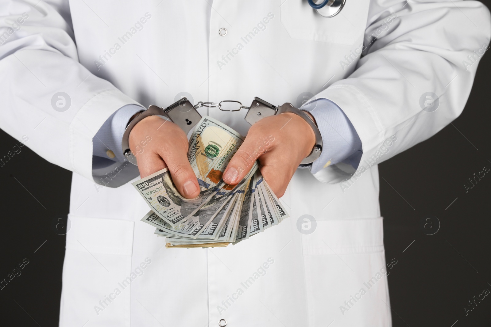 Photo of Doctor in handcuffs with bribe on black background, closeup. Corrupted medicine