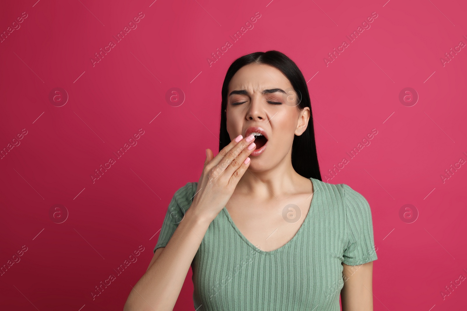 Photo of Young tired woman yawning on pink background